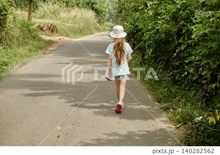 Monitor lizard running across countryside road as girl stands amazed Monitor lizard running across countryside road as girl stands amazed 140282562