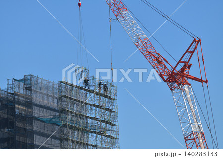 とび職　タワークレーンで仮設足場組立ての作業風景 140283133
