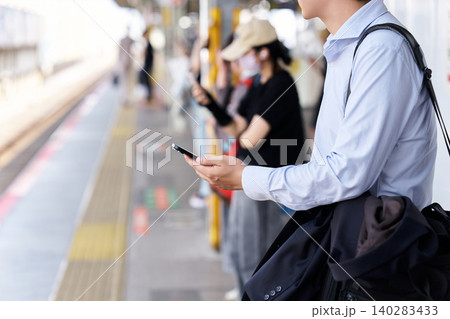 駅のホームでスマートフォンを操作するシャツ姿の顔無しで匿名の日本人の男性のビジネスマン 駅のホームでスマートフォンを操作するシャツ姿の顔無しで匿名の日本人の男性のビジネスマン 140283433