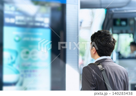 公共バス停の時刻表を見るスーツ姿の30代日本人男性会社員の顔無しの後ろ姿 140283438