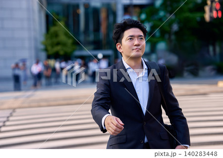 夕方の帰宅ラッシュ時のオフィス街の交差点の横断歩道を歩く30代の帰宅中の日本人の男性ビジネスマン 140283448