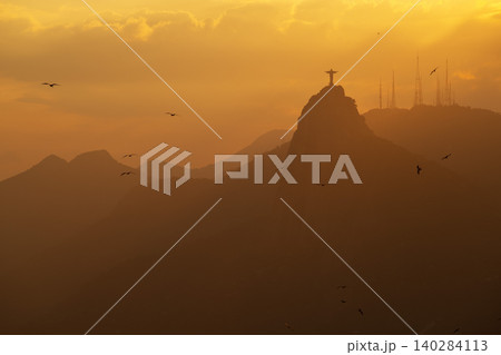 Serene sunset silhouette over mountain in Rio de Janeiro Brazil with famous statue and golden light 140284113