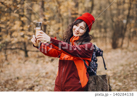Middle aged woman holds smartphone to record video while hiking in autumn forest. social media storytelling, capturing travel memories, vlogging gear for hikers. Middle aged woman holds smartphone to record video while hiking in autumn forest. social media storytelling, capturing travel memories, vlogging gear for hikers. 140284138