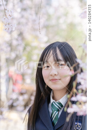 満開の桜と女子生徒の笑顔 前ボケ 青春のイメージ 140284355