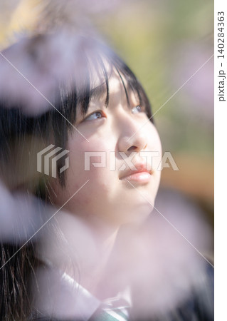 満開の桜と女子生徒の笑顔 前ボケ 青春のイメージ 140284363