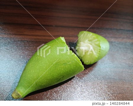 close up of green coconut on wooden table, Cut green fruit piece, Halved green vegetable, Fresh produce on wood close up of green coconut on wooden table, Cut green fruit piece, Halved green vegetable, Fresh produce on wood 140284844