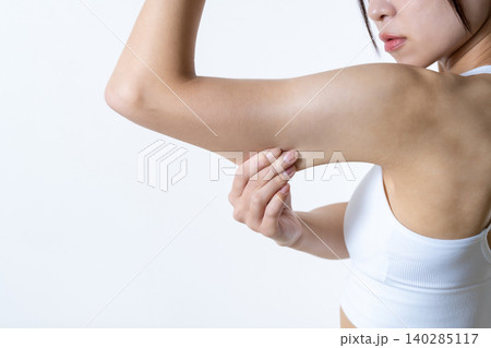体を鍛えているかっこいい女性 二の腕をつまんでたるみを確認する日本人女性 ダイエット 体を鍛えているかっこいい女性 二の腕をつまんでたるみを確認する日本人女性 ダイエット 140285117