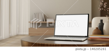 White screen laptop with books and vase on round wooden table across wall and curtain in living room White screen laptop with books and vase on round wooden table across wall and curtain in living room 140285281