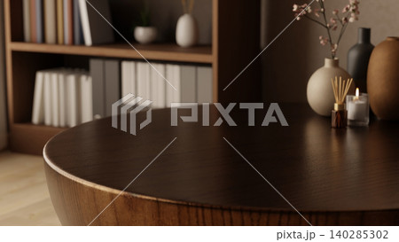 Diffuser and glass candle with flower vase on round wooden table across bookshelf in cafe or library. Diffuser and glass candle with flower vase on round wooden table across bookshelf in cafe or library. 140285302