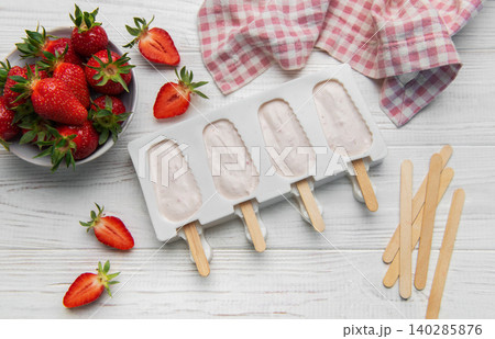 Strawberry popsicles in making process on white wooden surface Strawberry popsicles in making process on white wooden surface 140285876