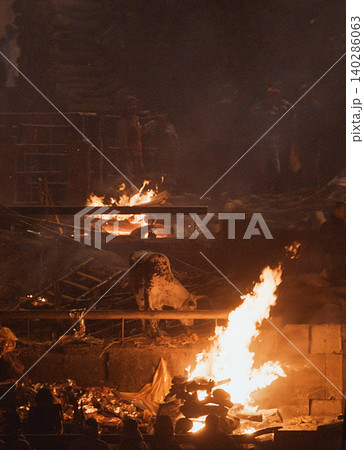 Varanasi, Uttar Pradesh, India. Cremation in process on Manikarnika Ghat. Cow Near Burning Pyre in Varanasi 140286063