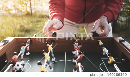 Man playing table football outdoors in a garden setting, capturing casual recreation as a gateway to the Football World Cup 140286360