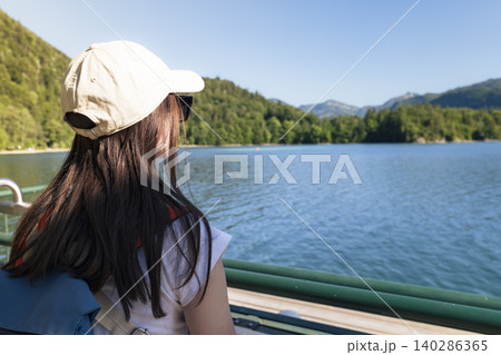 Young woman looking at the lake from a pier at Lake Wolfgangsee in the Austrian Alps, conveying everyday mindfulness in nature Young woman looking at the lake from a pier at Lake Wolfgangsee in the Austrian Alps, conveying everyday mindfulness in nature 140286365