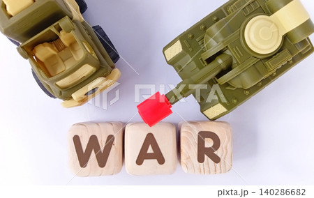 Top view of a military toy tank with wooden cubes labeled WAR. Illustration of war and conflict. Top view of a military toy tank with wooden cubes labeled WAR. Illustration of war and conflict. 140286682