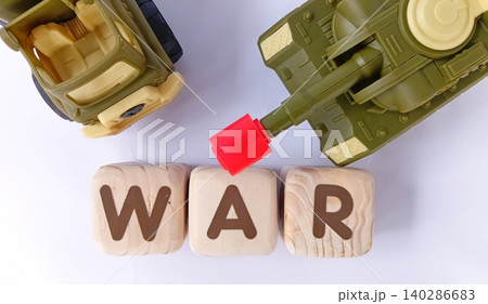 Top view of a military toy tank with wooden cubes labeled WAR. Illustration of war and conflict. Top view of a military toy tank with wooden cubes labeled WAR. Illustration of war and conflict. 140286683