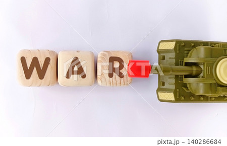 Top view of a military toy tank with wooden cubes labeled WAR. Illustration of war and conflict. Top view of a military toy tank with wooden cubes labeled WAR. Illustration of war and conflict. 140286684
