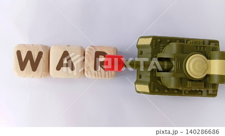 Top view of a military toy tank with wooden cubes labeled WAR. Illustration of war and conflict. Top view of a military toy tank with wooden cubes labeled WAR. Illustration of war and conflict. 140286686