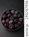 Juicy ripe fresh plum with water drops in gray plate on black background. Seasonal fruits. Selective focus, close-up. 140287896