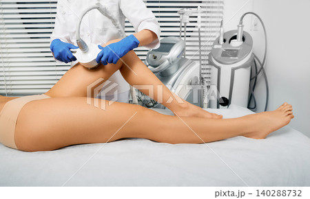 Woman's body slimming ultrasonic cavitation using ultrasound cavitation machine with a cosmetologist. Anti-cellulite therapy for female leg Woman's body slimming ultrasonic cavitation using ultrasound cavitation machine with a cosmetologist. Anti-cellulite therapy for female leg 140288732