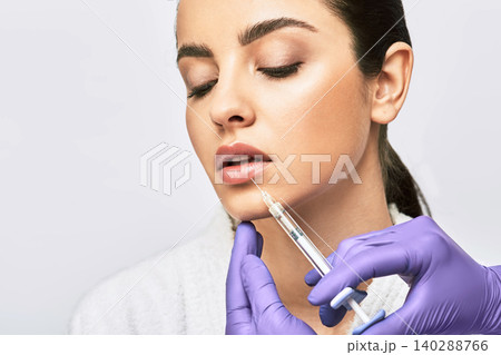 Lip augmentation procedure. Syringe with lips filler near beautiful woman's mouth, injections for increase lips shape 140288766