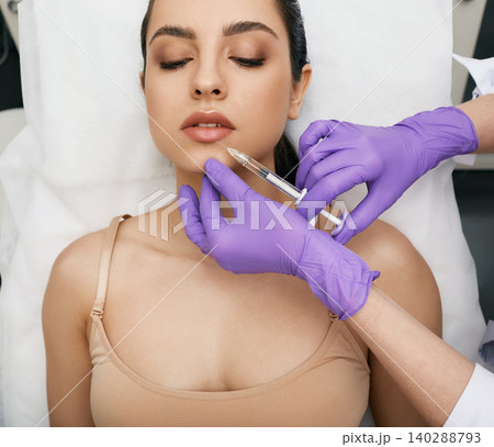 Lip augmentation procedure. Filler injection for beautiful woman lip augmentation with hyaluronic at a beauty salon Lip augmentation procedure. Filler injection for beautiful woman lip augmentation with hyaluronic at a beauty salon 140288793