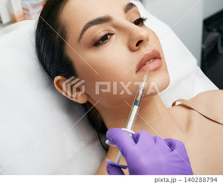 Lip augmentation procedure. Lips filler injection for beautiful woman's lip augmentation with beautician at cosmetology clinic 140288794