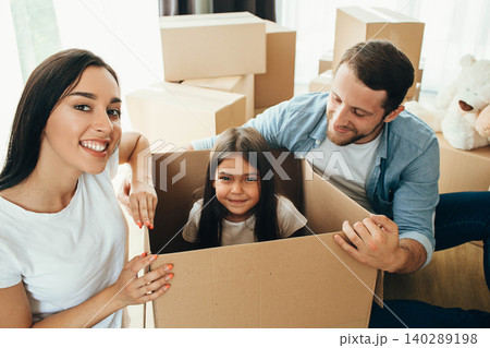 Happy family having fun while moving into new apartment. Mother, father and daughter together smiling, with Cardboard boxes on background Happy family having fun while moving into new apartment. Mother, father and daughter together smiling, with Cardboard boxes on background 140289198
