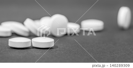 White round medical pills scattered on a dark slate surface 140289309