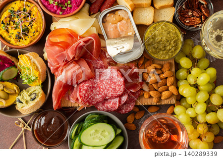 Enjoy a vibrant charcuterie board filled with assorted cheeses, savory sausages, creamy hummus, nuts, and colorful vegetables. Perfect for sharing at a casual gathering Enjoy a vibrant charcuterie board filled with assorted cheeses, savory sausages, creamy hummus, nuts, and colorful vegetables. Perfect for sharing at a casual gathering 140289339