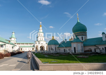 Historic Russian Orthodox Monastery Gate Tower With Golden Cross and White Fortress Walls Under Blue Sky Historic Russian Orthodox Monastery Gate Tower With Golden Cross and White Fortress Walls Under Blue Sky 140289431