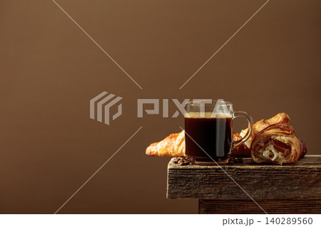 Black coffee with croissants on an old wooden table. Black coffee with croissants on an old wooden table. 140289560