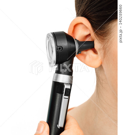 Hearing exam. Otoscope and ear of a child close-up isolated on white. Hearing test in a clinic. 140289660