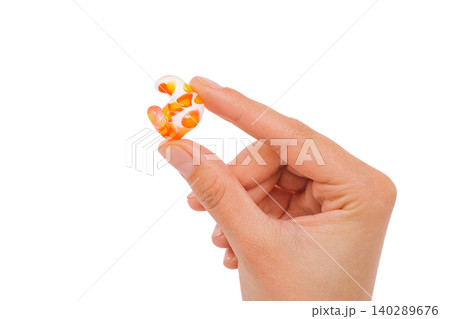 Isolated on white earplug in female hand. Personally molded earplugs close-up. Part of the set Isolated on white earplug in female hand. Personally molded earplugs close-up. Part of the set 140289676