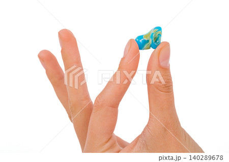 Isolated on white earplug in female hand. Personally molded earplugs close-up. Part of the set 140289678