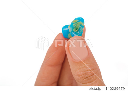 Isolated on white earplug in female hand. Personally molded earplugs close-up. Part of the set 140289679