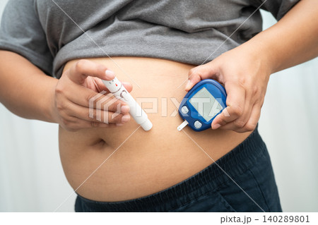 Asian woman injecting herself diabetes injecting insulin in stomach at home. 140289801