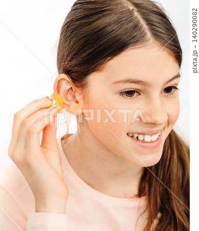 Individual earplugs for children. Girl holding individual ear plugs near ear, closeup 140290082
