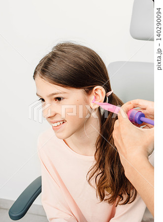 Otolaryngologist making earplugs from an impression of an individual child ear. Personally molded earplugs Otolaryngologist making earplugs from an impression of an individual child ear. Personally molded earplugs 140290094