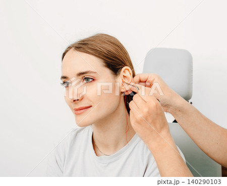 Otolaryngologist making earplugs from an impression of an individual woman ear. Personally molded earplugs Otolaryngologist making earplugs from an impression of an individual woman ear. Personally molded earplugs 140290103