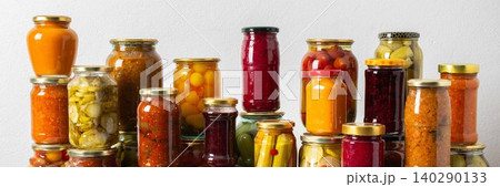 Canned vegetables and fruits are stacked on a shelf, prepared for winter use. Various jars hold different preserves, showcasing careful efforts for storing food during the season, banner Canned vegetables and fruits are stacked on a shelf, prepared for winter use. Various jars hold different preserves, showcasing careful efforts for storing food during the season, banner 140290133