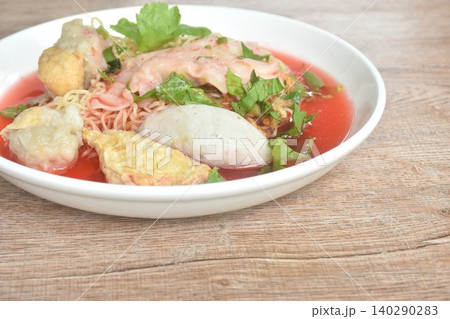 Chinese yellow egg noodles with fish ball and pork dumpling in red soup on plate Chinese yellow egg noodles with fish ball and pork dumpling in red soup on plate 140290283