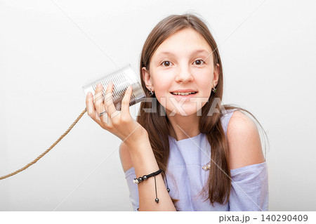 Positive girl with a tin can telephone near the ear, playing in retro connected chat. I hear you well, child isolated on white Positive girl with a tin can telephone near the ear, playing in retro connected chat. I hear you well, child isolated on white 140290409