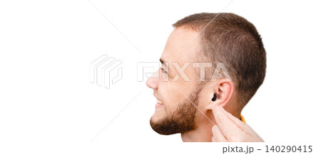 Positive male patient using an intra-ear hearing aid in his ear can hear the sounds of the surrounding world. Hearing solutions for deafness treatment, isolated on white 140290415