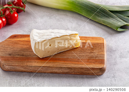Wedge of soft brie cheese on wooden board with tomatoes and leeks 140290508