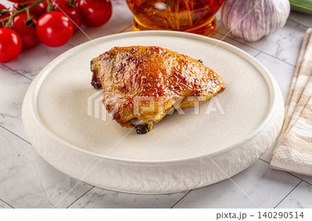 Roasted chicken thigh on white ceramic plate with cherry tomatoes and garlic Roasted chicken thigh on white ceramic plate with cherry tomatoes and garlic 140290514