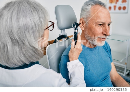 Senior man during ear test with audiologist at audiology. Diagnosis of impairment and hearing testing to senior people, otoscopy Senior man during ear test with audiologist at audiology. Diagnosis of impairment and hearing testing to senior people, otoscopy 140290586