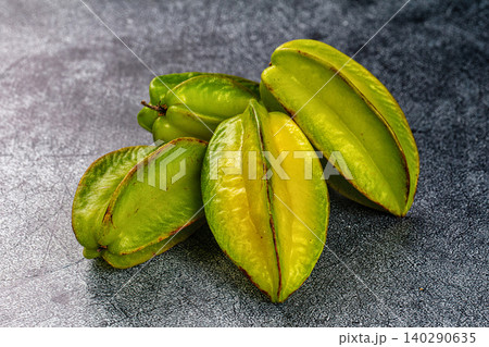 Fresh green starfruits on dark stone surface Fresh green starfruits on dark stone surface 140290635