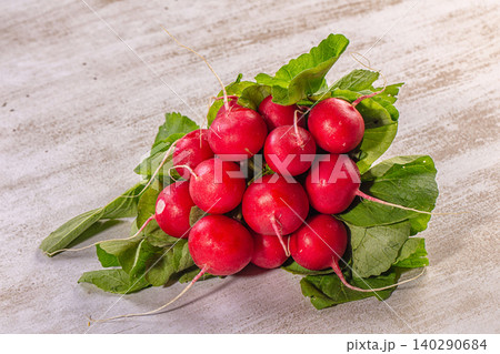 Fresh red radishes with green leaves on rustic wooden surface Fresh red radishes with green leaves on rustic wooden surface 140290684