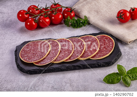 Sliced salami on slate board with fresh tomatoes and basil 140290702