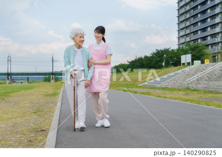 土手を散歩する日本人シニア女性と若い女性介護士 土手を散歩する日本人シニア女性と若い女性介護士 140290825